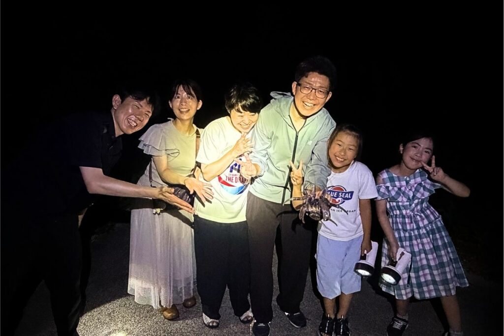 石垣島の星空ジャングルナイトツアーで捕まえたヤシガニと一緒に家族みんなで記念写真を撮影する様子 RUANOA